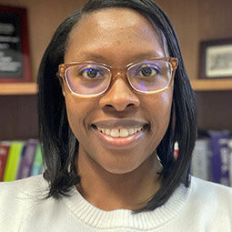 Taryn, a Black woman with glasses, smiling.